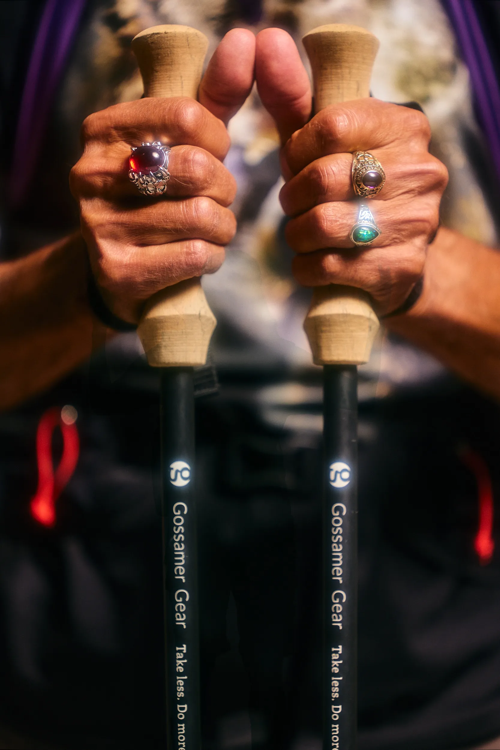 Hands with silver rings gripping two Gossamer Gear LT5 trekking poles