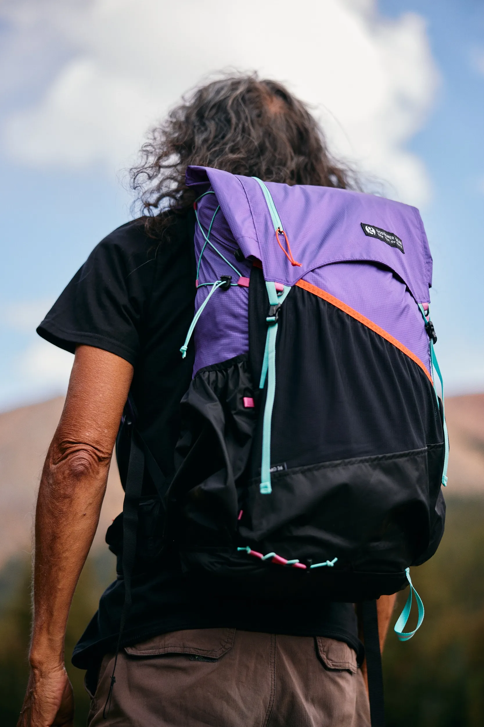 Back view of a hiker carrying the purple and black Kumo 36 pack